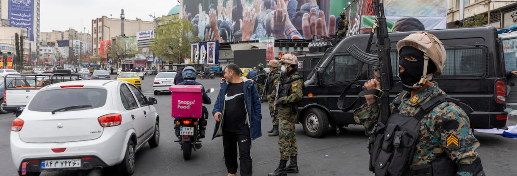 A police officer stands guard beneath a poster of Iran's former leader, Ayatollah Ali Khamenei, on 10 March 2026 in Tehran. Photo by Majid Saeedi via Getty Images