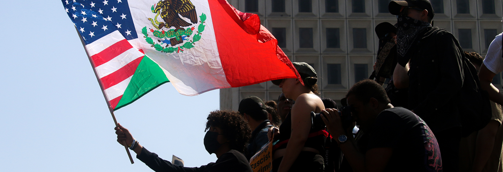 A demonstrator waves a combination Mexican-American flag during a protest against ICE raids and the deployment of the National Guard at The Federal Building in Downtown Los Angeles on June 9, 2025.