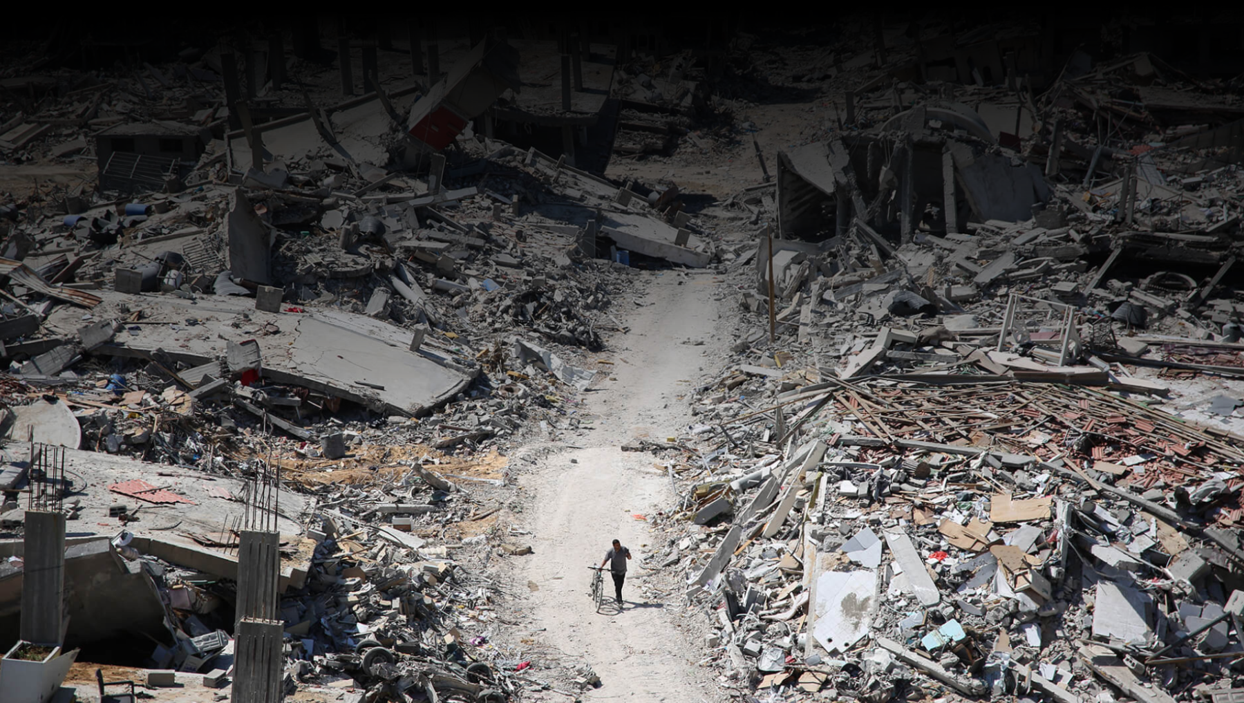 Editorial photo of destruction and a man walking with a bicycle in Gaza