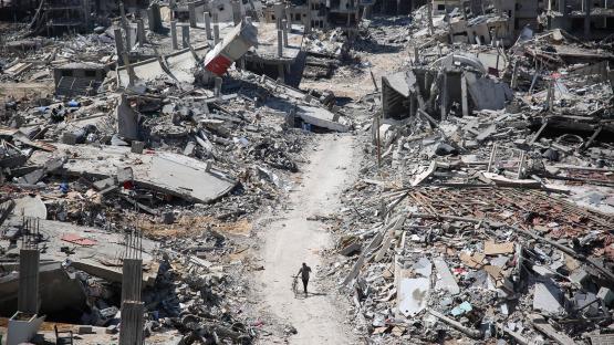 Editorial photo of destruction and a man walking with a bicycle in Gaza