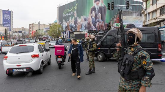 A police officer stands guard beneath a poster of Iran's former leader, Ayatollah Ali Khamenei, on 10 March 2026 in Tehran. Photo by Majid Saeedi via Getty Images