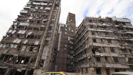 Cars drive past the damaged facade of the Gandhi Hospital in Tehran, which was hit on 1 March, when a projectile struck a state TV communications tower and nearby buildings across the street, during the joint US-Israeli military campaign on Iran. 