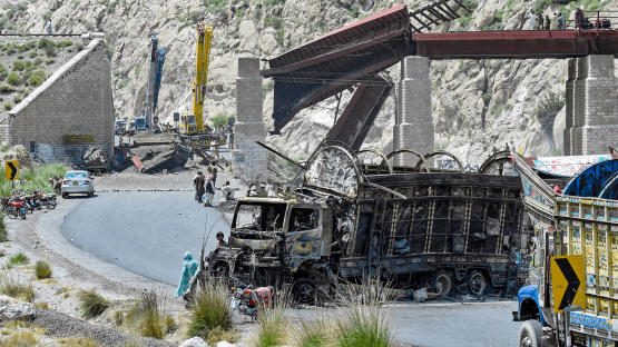 Residents stand beside a charred vehicle near a collapsed railway bridge the morning after a blast by separatist militants at Kolpur in Bolan district, Balochistan province, on 27 August 2024.