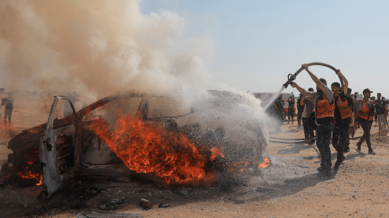 Firefighters attempt to extinguish a fire following an Israeli airstrike that hit a vehicle and killed a senior police official in Gaza City on 13 August 2026. 