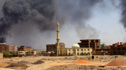 A man walks while smoke rises above buildings after aerial bombardment, during clashes between the paramilitary Rapid Support Forces and the army in Khartoum North, Sudan, May 1, 2023. 